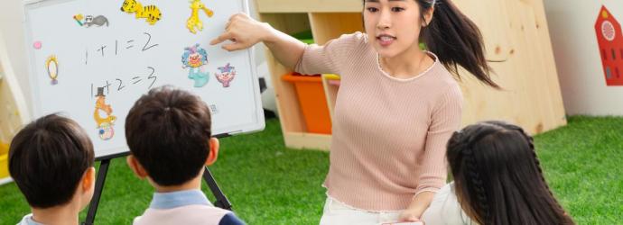 an image of a teacher on the floor in a classroom with three early years pupils